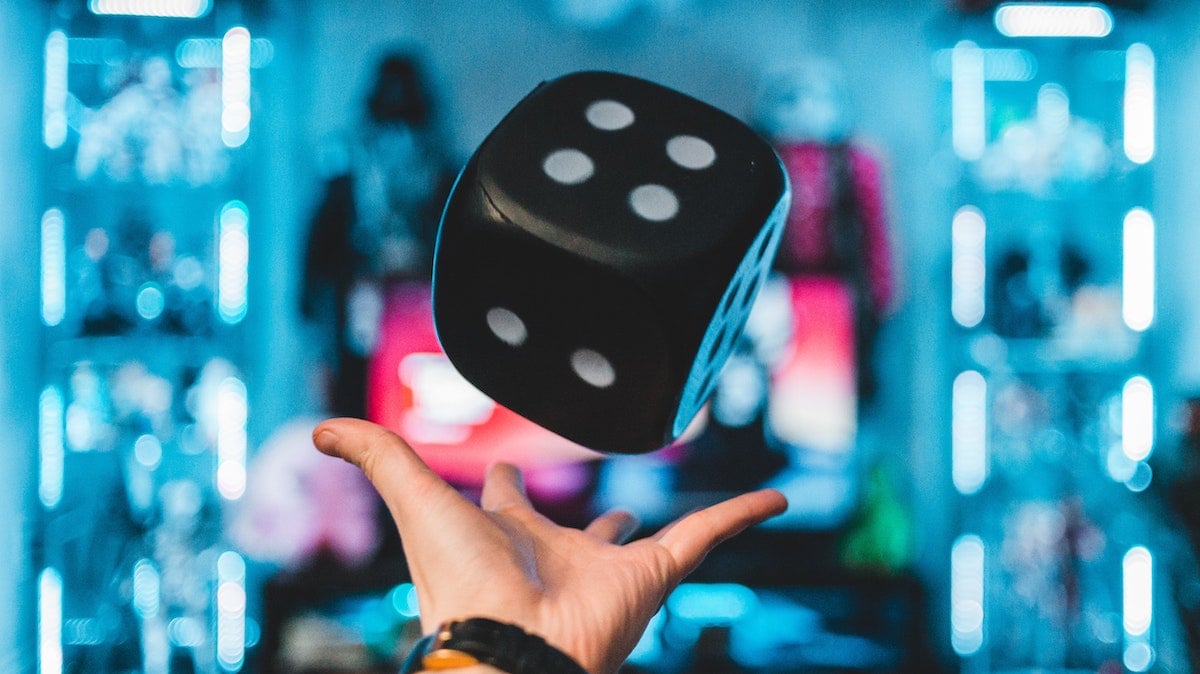 a hand throwing a big die into the air in a flashy-looking arcade